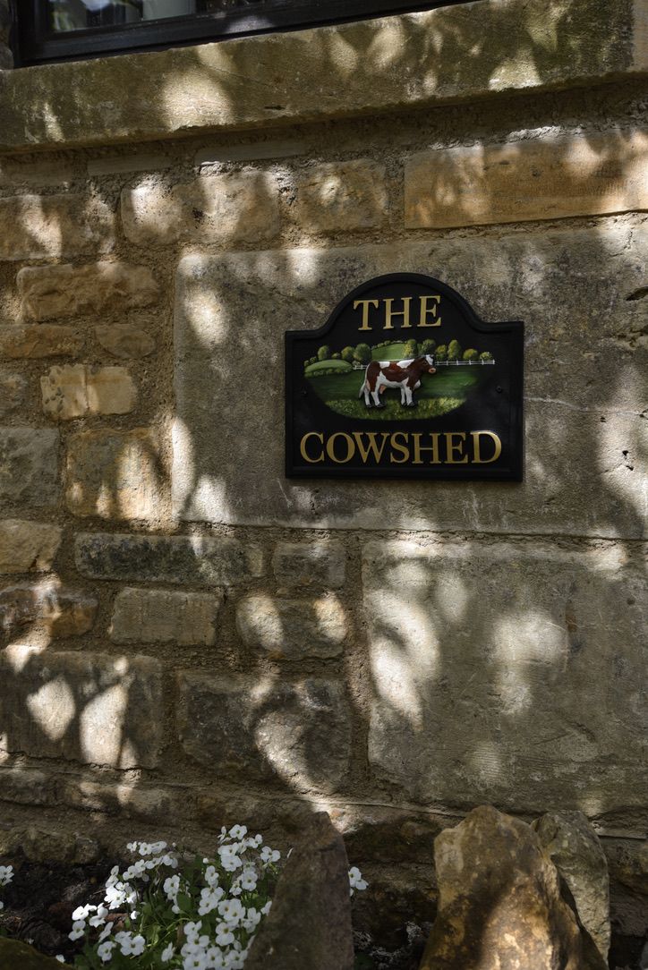 Un muro di pietra con un cartello che dice 'The Cowshed'.