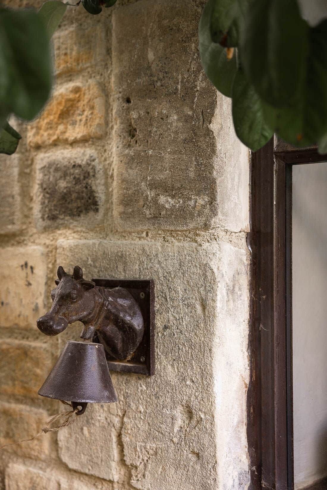 A stone wall with a metal horse figure and a bell mounted on it.