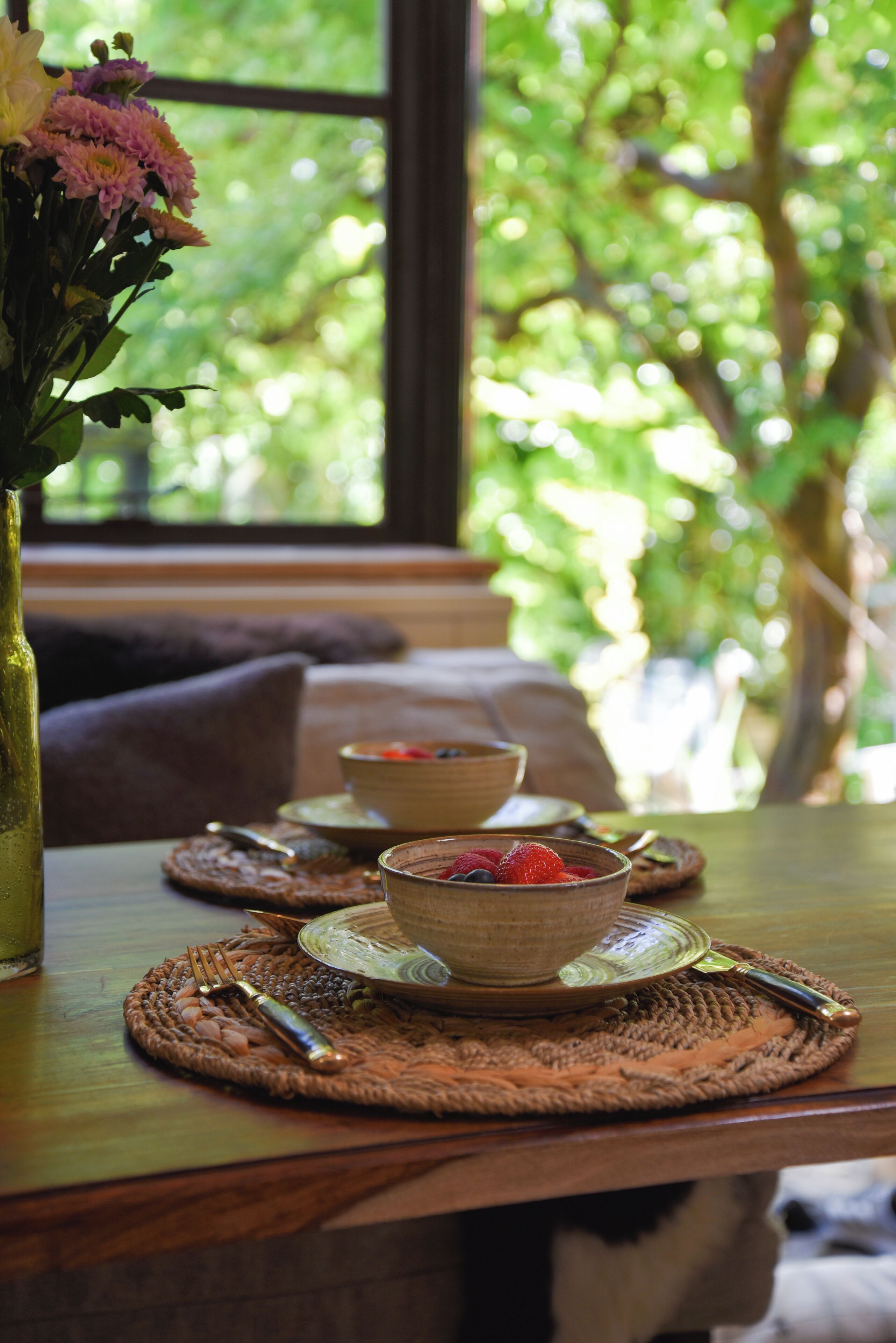 Une table à manger avec des sets de table, des bols et des couverts.