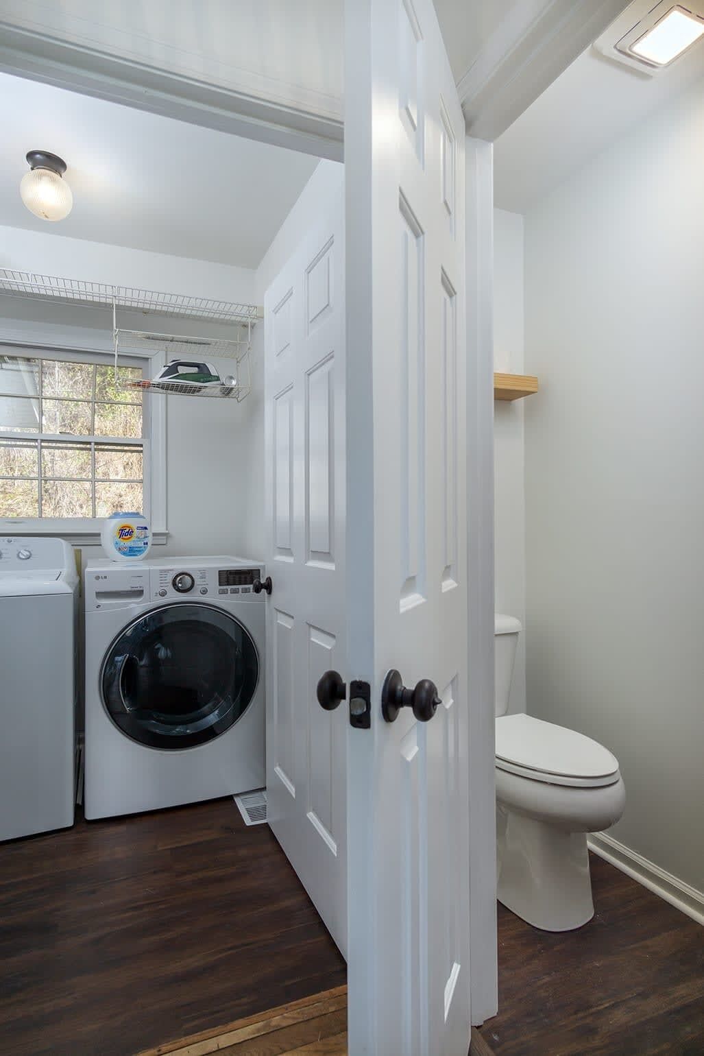 A laundry room with a washing machine, dryer, and ironing board.