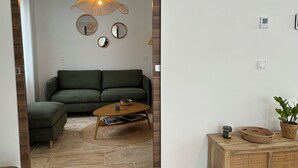 Ein modernes Wohnzimmer mit einem grünen Sofa, einem Holztisch und einer außergewöhnlichen gewebten Leuchte.