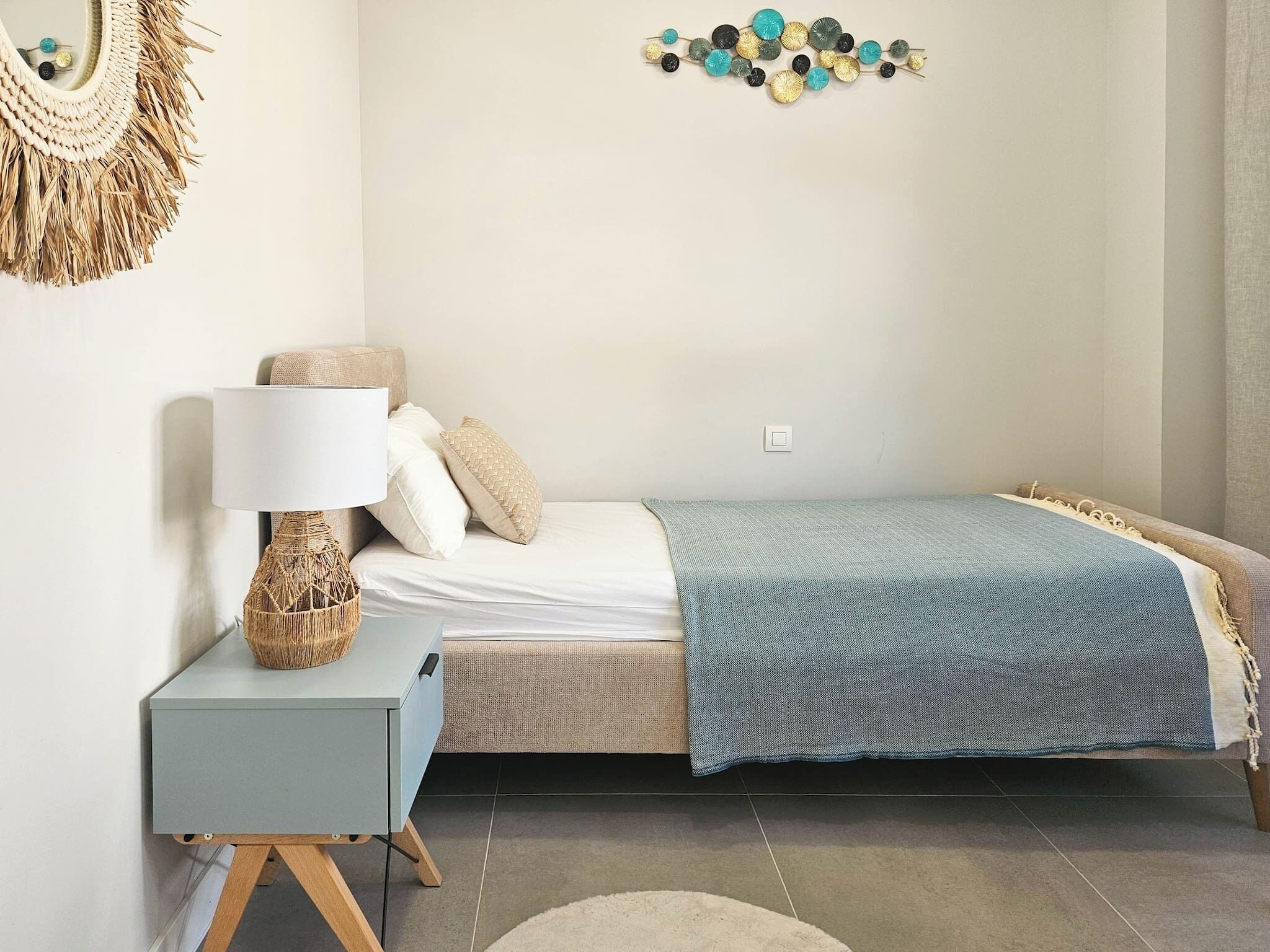 Une chambre à coucher avec un lit, une table de chevet avec une lampe, un élément de décoration murale et un tapis à motifs.