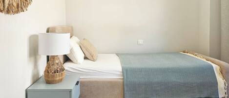 Une chambre à coucher avec un lit, une table de chevet avec une lampe, un élément de décoration murale et un tapis à motifs.