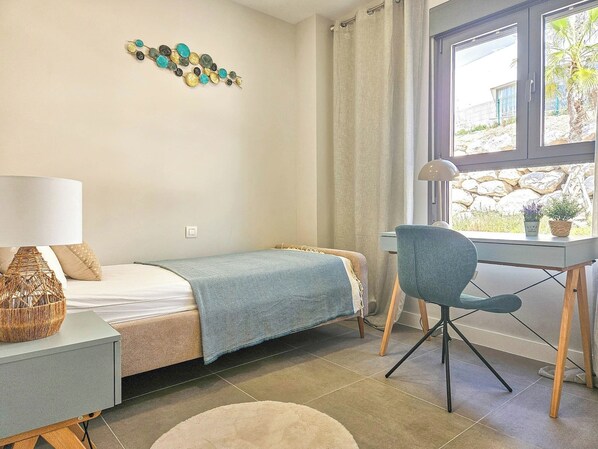 Un dormitorio con cama, un escritorio, una silla, una lámpara y un adorno en la pared.