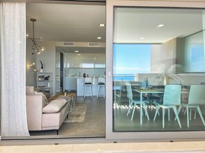 Un salon moderne comprenant un canapé, une table basse et un coin repas avec une table et des chaises en verre.