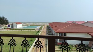 A hotel with a pool, a tennis court, and a view of the sea. - Tarangamala Resort (Kanthi)