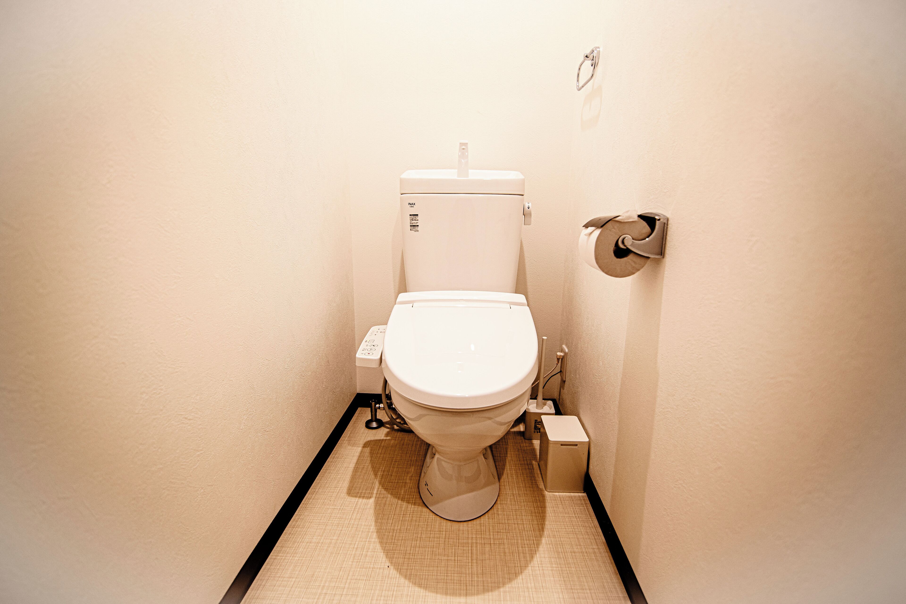 Un bany petit i compacte amb un vàter blanc, un bidet fixat a la paret i un suport de paper higiènic.