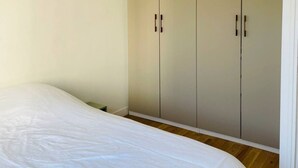 A bedroom with a large bed, a wardrobe, and a hanging light fixture. - Chic 3 Pièces Familial Pour Bébé au Cœur de Paris (Paris)