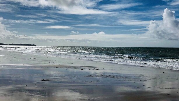 Ein Strand mit weitem, sandigen Uferbereich und dem Meer.