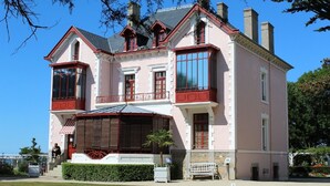 Ein großzügiges, zweistöckiges Gebäude mit einer symmetrischen Fassade, großen Fenstern und einem markanten Balkon.