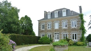 A large stone building with multiple windows and a garden pathway leading to the entrance.
