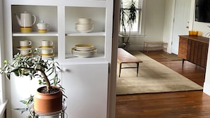A modern kitchen with white cabinetry, a built-in pantry, and a variety of kitchenware.