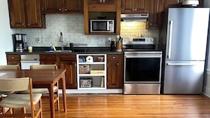 A kitchen with wooden cabinets, a microwave, a stove, and a refrigerator.