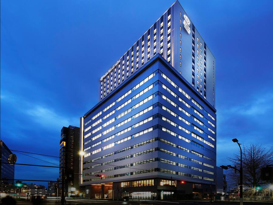 Een modern hotelgebouw met meerdere verdiepingen en een opvallend logo bovenaan.