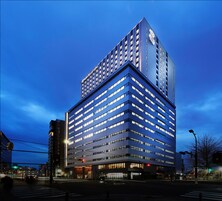 A modern hotel building with multiple floors and a prominent logo on the top.