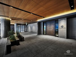 A modern hotel lobby with a wooden ceiling, large pillars, and a view of the cityscape through the glass doors.