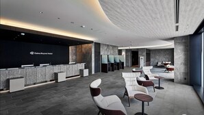 Zona d'entrada d'un hotel modern, amb un taulell de recepció negre, zona de seients i una finestra gran.