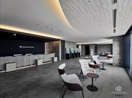 A modern hotel reception area with a black reception desk, seating area, and a large window.