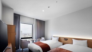 Habitació d'hotel amb dos llits, televisió, escriptori i vista a la ciutat.