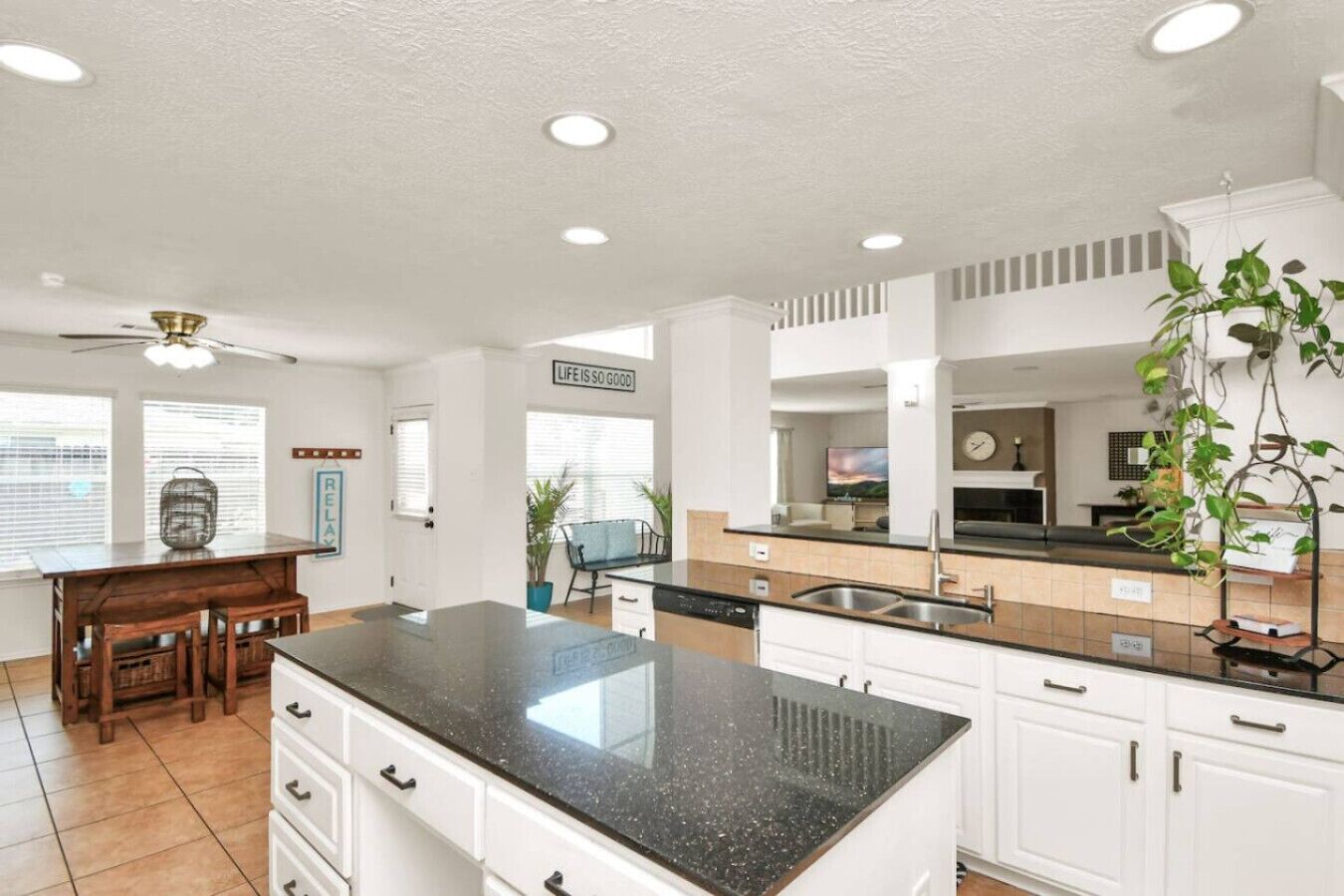 Une cuisine moderne dotée d’un îlot central, de meubles blancs et d’un ventilateur de plafond.