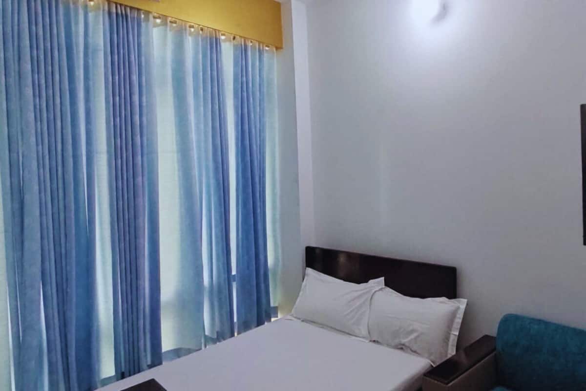 Une chambre à coucher avec un lit, des oreillers blancs, une table de chevet et une chaise bleue.