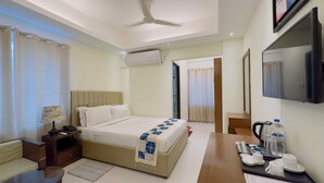 A hotel room with a bed, bedside table, lamp, TV, and a desk with a water bottle and cups. - Hotel The Grand Hyatt Dhaka (Dhaka)