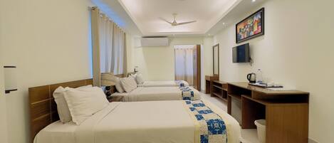 A hotel room with two beds, a desk, a television, and a ceiling fan.