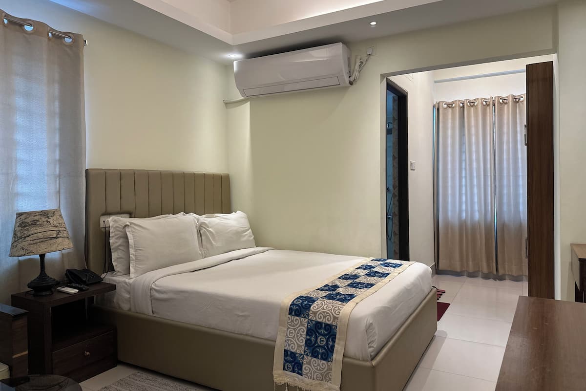 Une chambre d’hôtel équipée d’un lit, d’une table de chevet, d’une lampe et d’un appareil de climatisation.