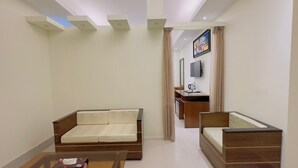 A modern living room with a sofa, a small table, and a bed. There is a TV mounted on the wall and a painting above it. - Hotel The Grand Hyatt Dhaka (Dhaka)