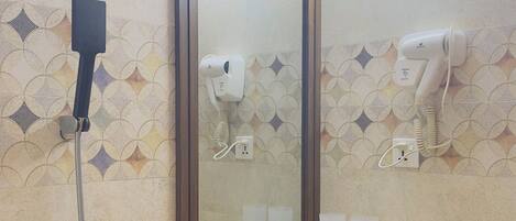 Ein Badezimmer mit Dusche, Waschbecken, Spiegel und Föhn.