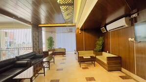 A modern hotel lobby with leather sofas, a wooden reception desk, and a large air conditioning unit. - Hotel The Grand Hyatt Dhaka (Dhaka)