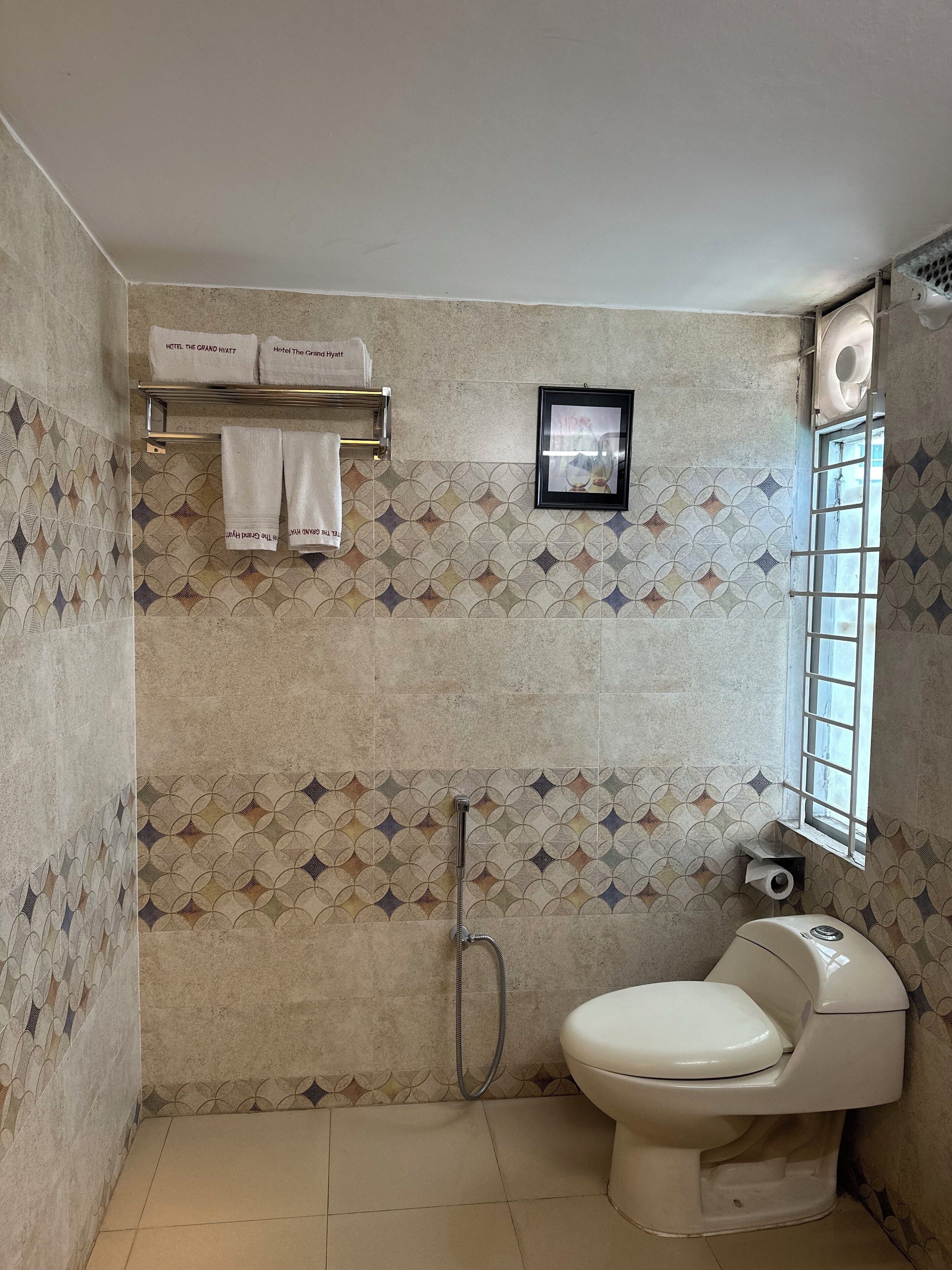 A bathroom with a toilet, a shower, and a towel rack with towels.