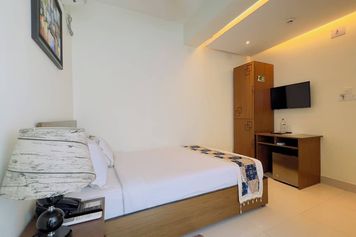 Une chambre d’hôtel moderne équipée d’un lit, d’un bureau, d’une télévision et d’une armoire.