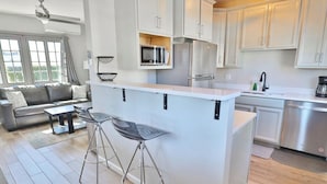A modern kitchen with a central island, bar stools, and stainless steel appliances. - Campus Casita close to U of A and shopping (Tucson)