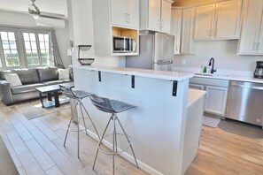 A modern kitchen with a central island, bar stools, and stainless steel appliances. - Campus Casita close to U of A and shopping (Tucson)