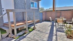 A patio area with a wooden deck, outdoor seating, and a brick wall. - Campus Casita close to U of A and shopping (Tucson)