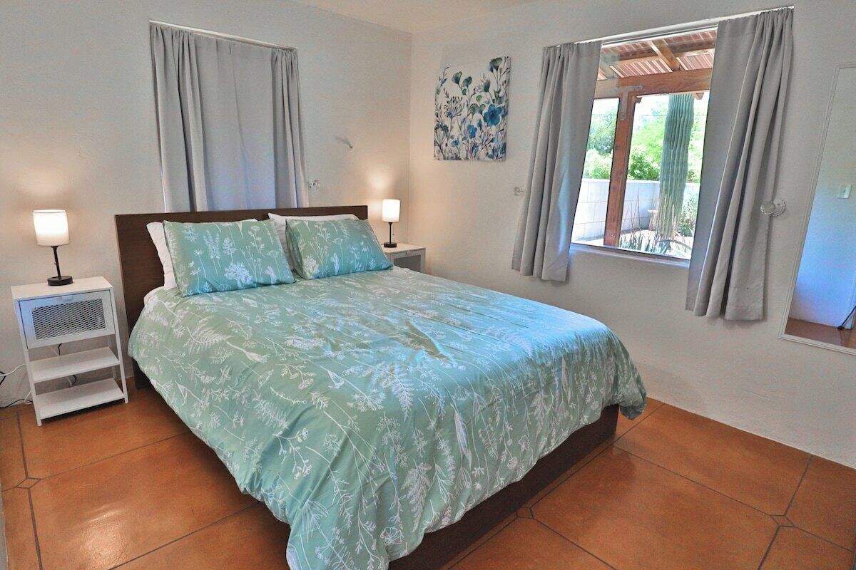 A bedroom with a bed, nightstands, a window, and a ceiling fan.