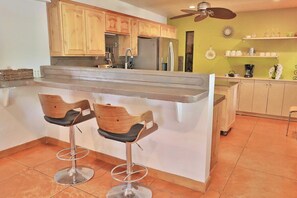 A kitchen with wooden cabinets, a central island with bar stools, and a ceiling fan. - Pet Friendly Catalina Haven (Tucson)