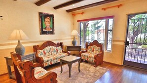 A living room with wooden furniture, a sofa, two armchairs, a coffee table, and a painting on the wall.