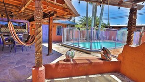 A pool area with a hammock, a decorative pig statue, and a fenced pool.