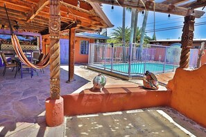 A pool area with a hammock, a decorative pig statue, and a fenced pool.
