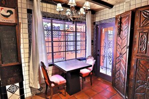A room with a table and chairs, a window with decorative ironwork, and a door with intricate patterns. - Hacienda Arevalo close to U of A (Tucson)