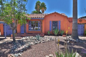 A house with a red facade, blue shutters, and a garden with rocks and plants. - Hacienda Arevalo close to U of A (Tucson)