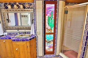 A bathroom with a wooden vanity, a mirror, a sink, and a shower enclosure.