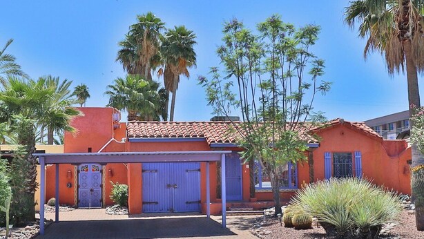 A building with a red facade, a blue door, and a covered entrance.
