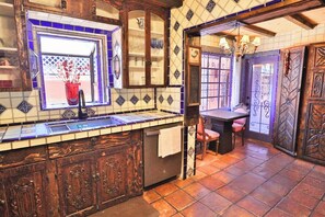 A kitchen with a tiled backsplash, wooden cabinets, and a window with a red vase.
