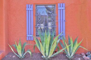 A building with a window featuring blue shutters and a decorative metal grille.
