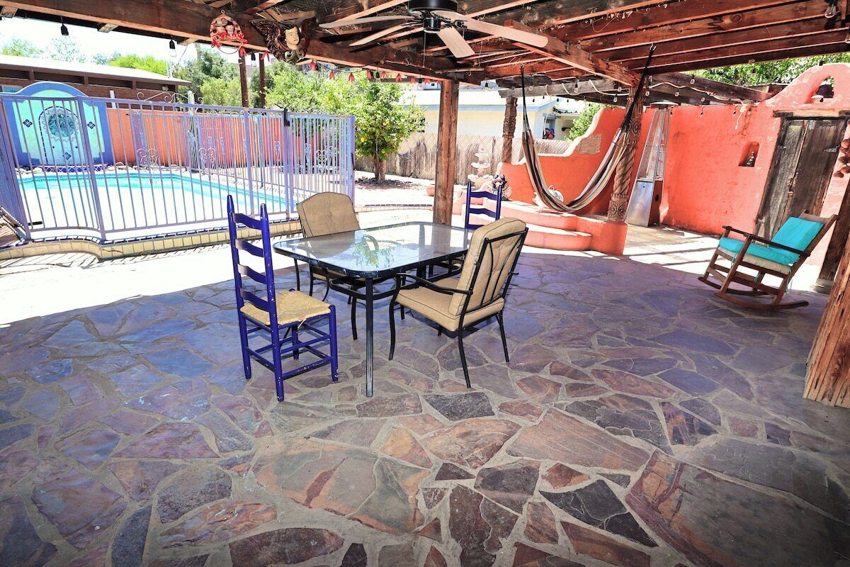 An outdoor patio with a stone floor, a glass table, and chairs.
