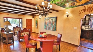 A dining area with a round table, red chairs, a chandelier, and artwork on the walls.