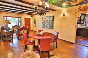 A dining area with a round table, red chairs, a chandelier, and artwork on the walls.